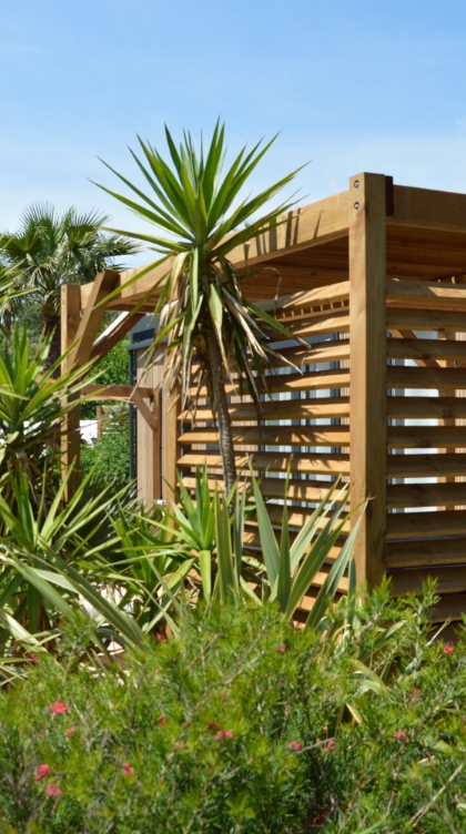 Image montrant une pergola en bois équipée d'un claustra, aménagée dans un jardin pour offrir une zone ombragée et esthétique.