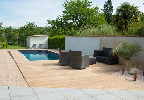 Terrasse haut de gamme en bois et céramique, avec une transition fluide entre les matériaux pour un rendu harmonieux en bord de piscine.